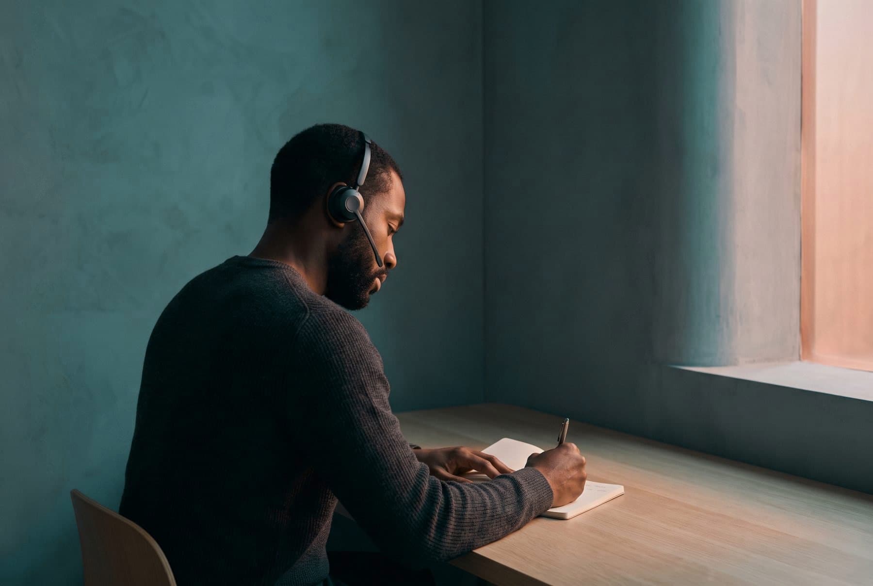 An agent in a headset writing notes during a call